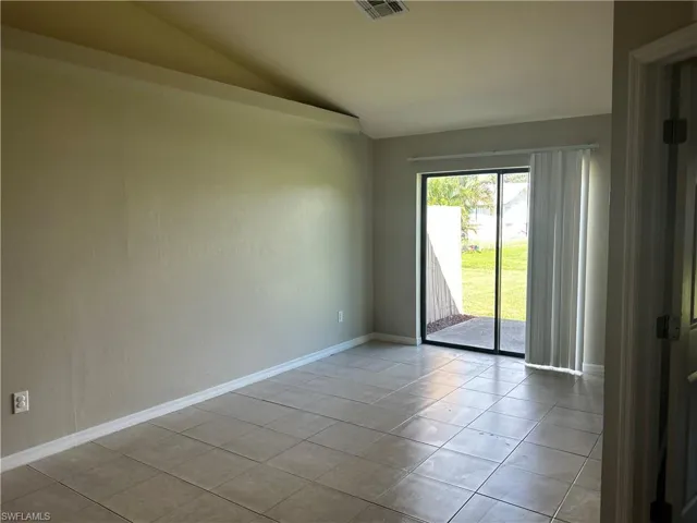 Spare room featuring lofted ceiling and light tile patterned floors