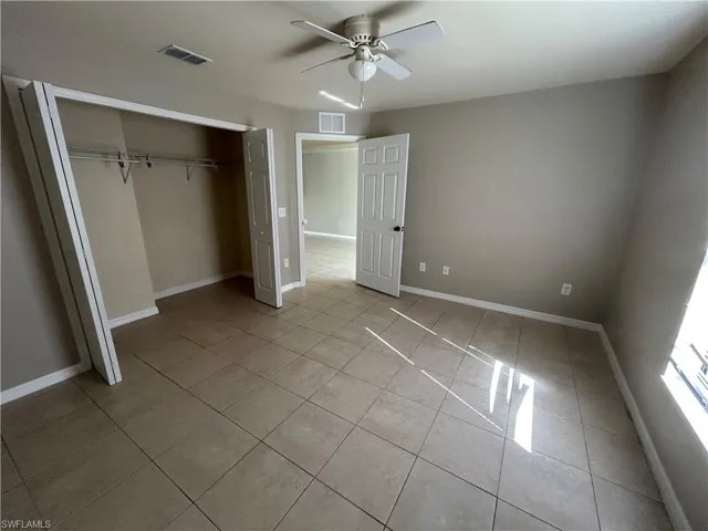Unfurnished bedroom with light tile patterned flooring, a closet, and ceiling fan