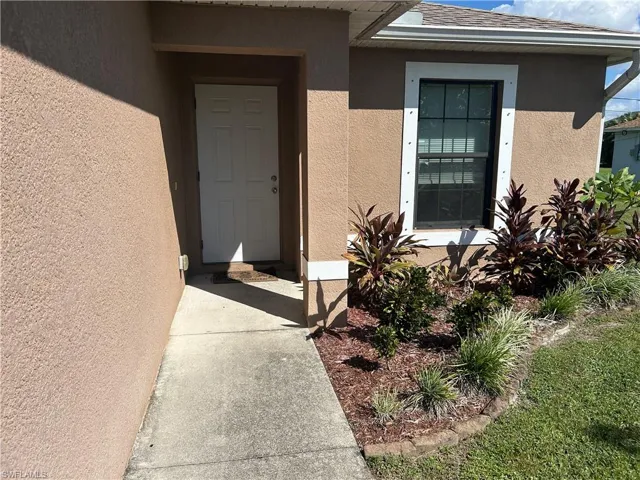 Property entrance with stucco siding and roof with shingles
