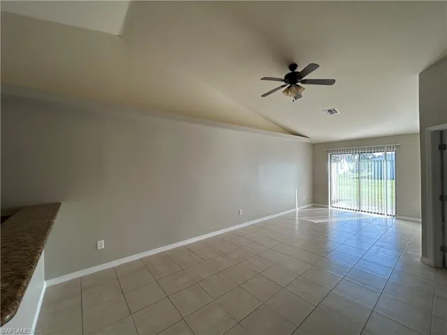 Unfurnished room with light tile patterned floors, vaulted ceiling, and a ceiling fan