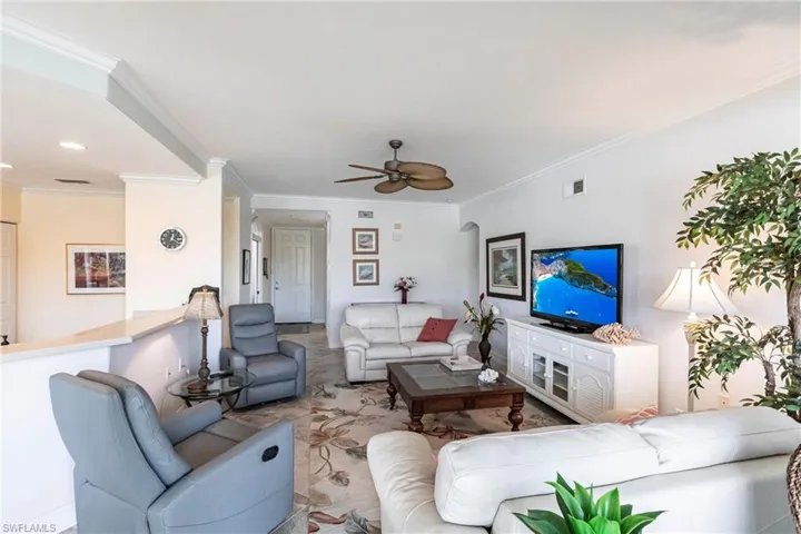 Living area featuring open layout, plenty of natural light, crown molding and panoramic views of the course