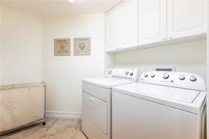 Laundry area featuring separate washer and dryer, cabinets, and on demand water heater