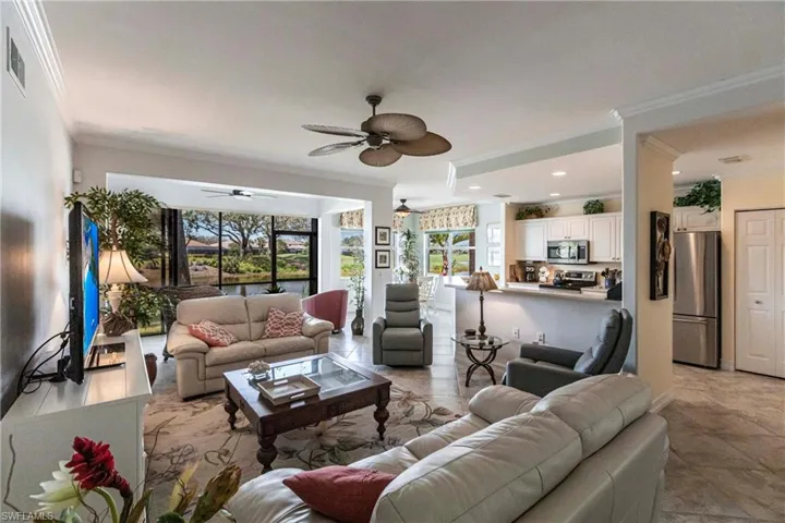Living area featuring open layout, plenty of natural light, crown molding and panoramic views of the course