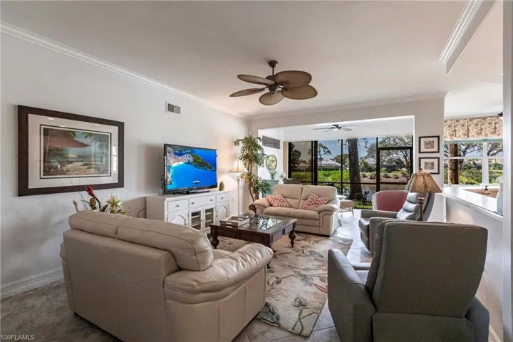 Living area featuring open layout, plenty of natural light, crown molding and panoramic views of the course