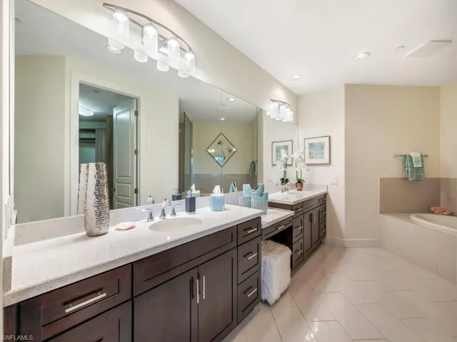 Bathroom featuring double vanity, light tile patterned flooring, a garden tub, and recessed lighting