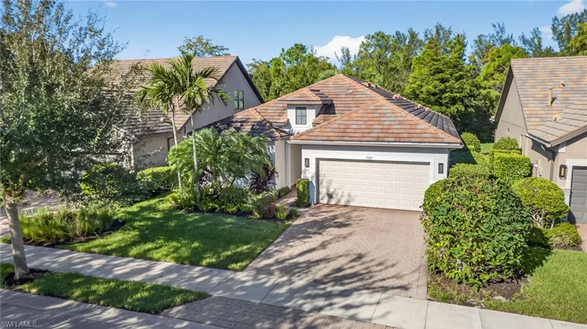View of front of home featuring decorative driveway, stucco siding, a front lawn, and an attached garage