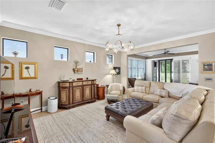 Living room featuring crown molding, ceiling fan, wood finished floors, and a chandelier