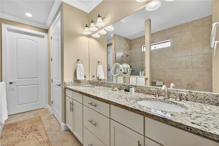 Bathroom with a shower stall, double vanity, light tile patterned floors, crown molding, and recessed lighting