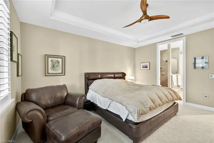 Carpeted bedroom with a raised ceiling and a ceiling fan