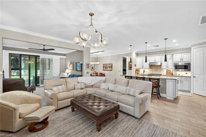 Living room with a ceiling fan, a chandelier, ornamental molding, light wood-type flooring, and recessed lighting