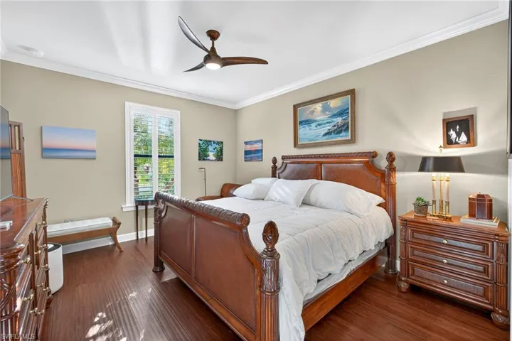 Bedroom with crown molding, dark wood-style flooring, and ceiling fan