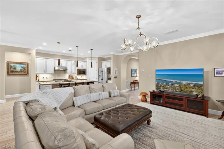 Living area featuring arched walkways, ornamental molding, recessed lighting, and a chandelier