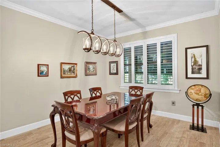 Dining space featuring ornamental molding, light wood-style floors, and a chandelier