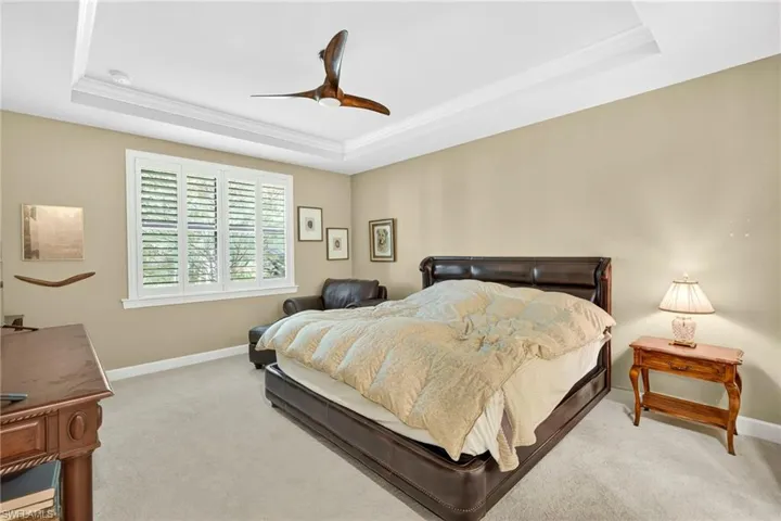 Bedroom featuring a raised ceiling, carpet, and ceiling fan