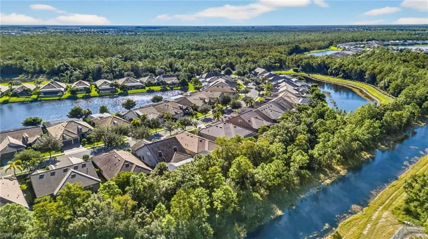 Aerial perspective of suburban area featuring a large body of water and a heavily wooded area