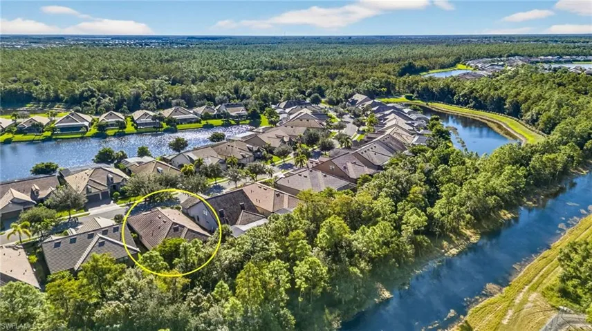 Aerial perspective of suburban area with a nearby body of water and a heavily wooded area