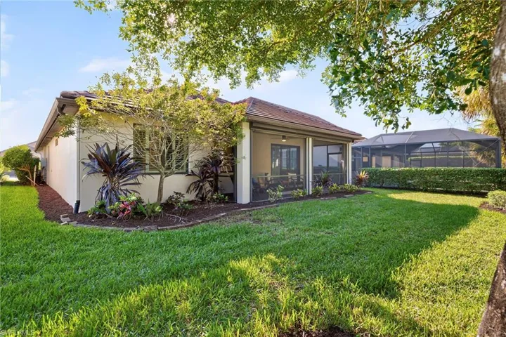 Rear view of property with a yard, a sunroom, stucco siding, and a lanai