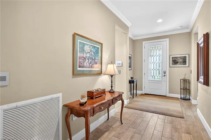 Foyer entrance featuring crown molding and light wood-style flooring