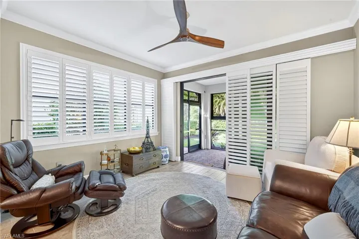 Living area featuring healthy amount of natural light, crown molding, wood finished floors, and a ceiling fan