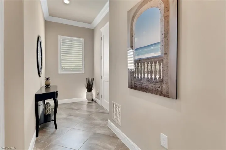 Hall featuring ornamental molding, healthy amount of natural light, and light tile patterned floors