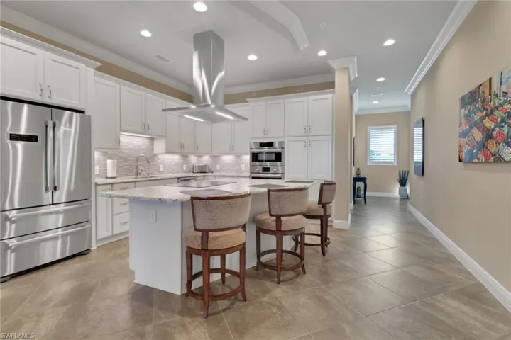 Kitchen featuring ornamental molding, appliances with stainless steel finishes, white cabinets, a center island, and a breakfast bar