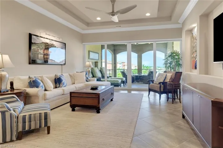 Living room featuring a tray ceiling, light tile patterned floors, a ceiling fan, and recessed lighting
