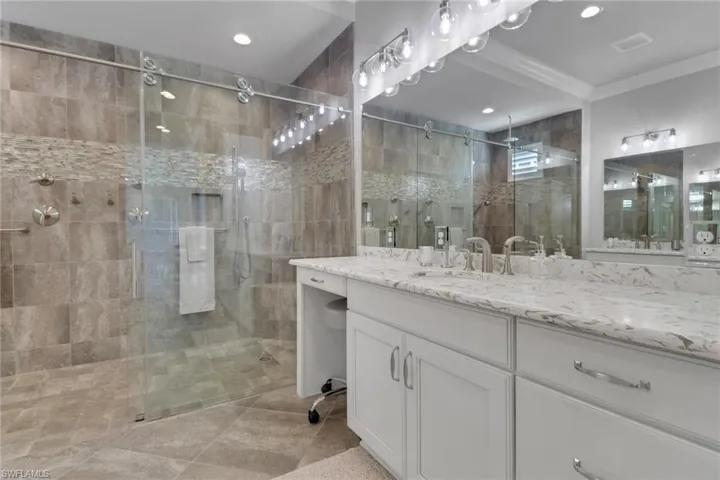 Primary Bathroom with a stall shower, vanity, light tile patterned floors, and recessed lighting