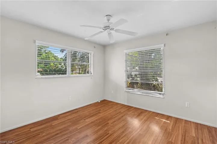 Unfurnished room featuring wood finished floors, a ceiling fan, and baseboards