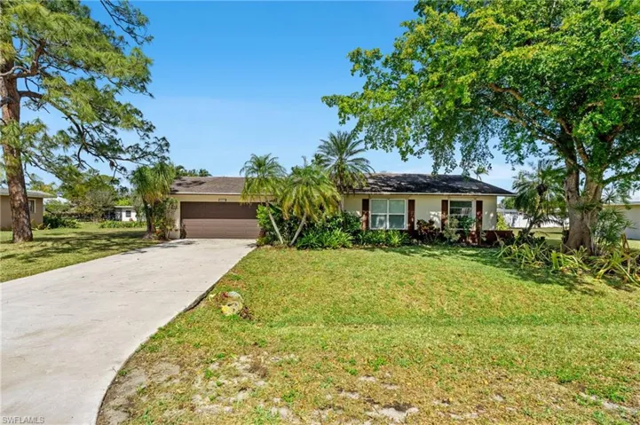 Ranch-style house featuring a front yard, concrete driveway, an attached garage, and stucco siding