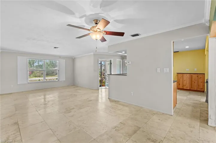 Empty room featuring ceiling fan, visible vents, baseboards, and ornamental molding