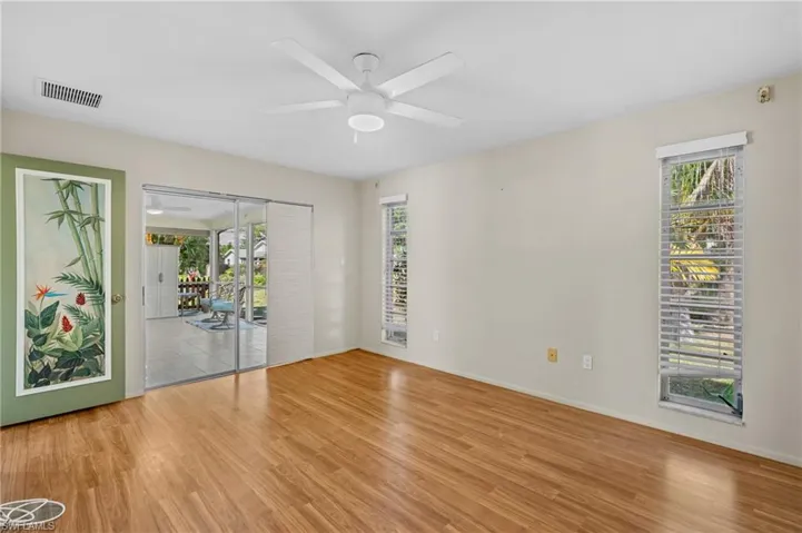 Unfurnished room featuring light wood-style floors, visible vents, plenty of natural light, and ceiling fan