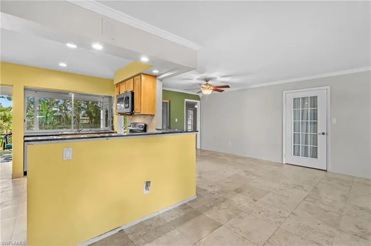 Kitchen with dark countertops, electric stove, crown molding, and ceiling fan