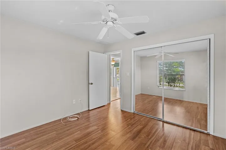 Unfurnished bedroom with ceiling fan, a closet, wood finished floors, and visible vents