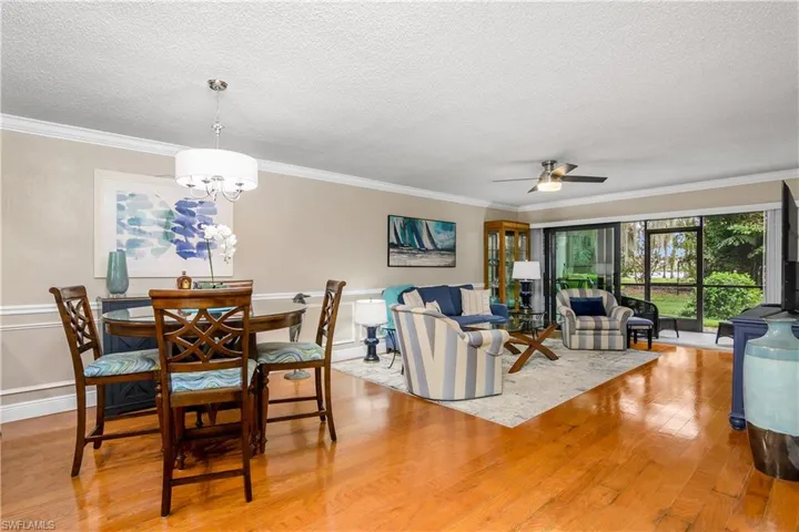 Dining room featuring ornamental molding, light hardwood / wood-style flooring, a textured ceiling, and ceiling fan with notable chandelier