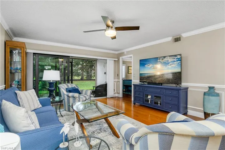 Living room with crown molding, wood-type flooring, a textured ceiling, and ceiling fan