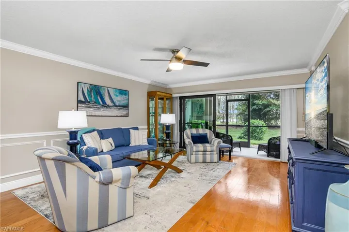 Living room with crown molding, wood-type flooring, a textured ceiling, and ceiling fan