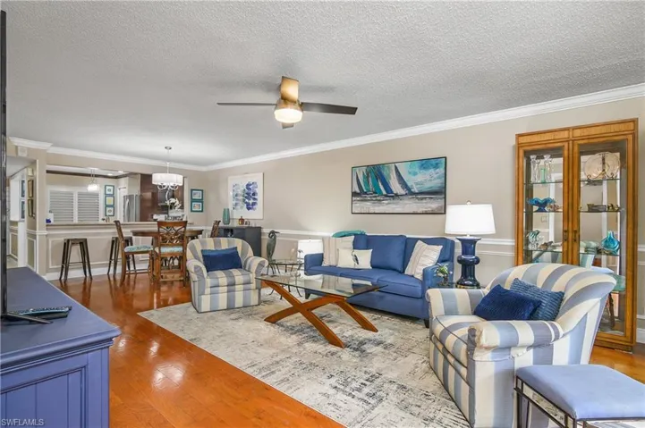 Living room featuring crown molding, wood-type flooring, plenty of natural light, and ceiling fan