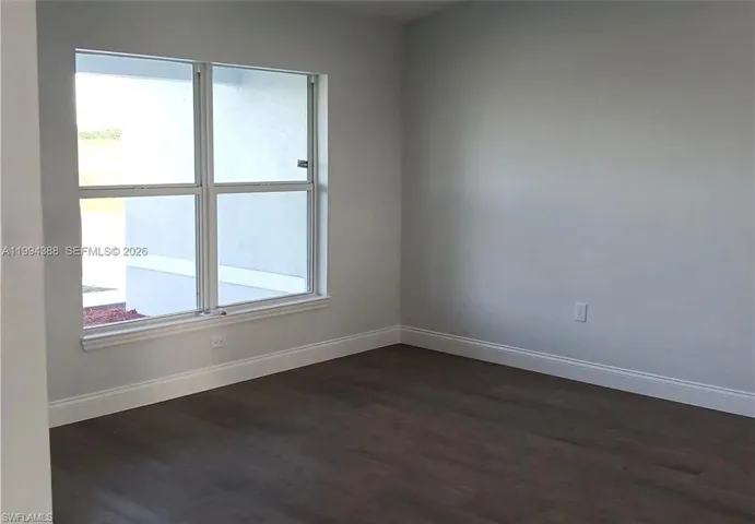 Interior space featuring wood-finish flooring, light gray wall paint, and white baseboards