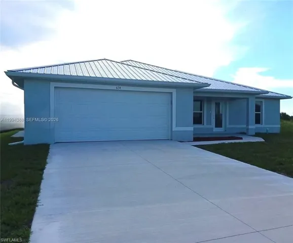 Contemporary exterior with light blue stucco siding, white trim, and a metal roof