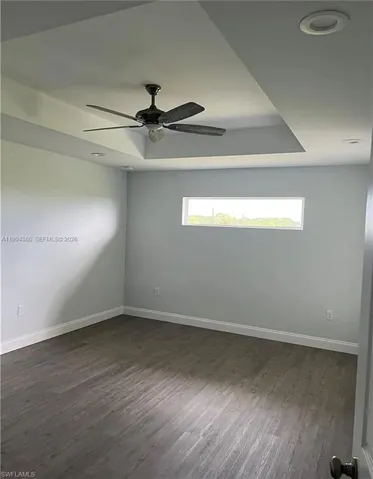 Spacious room featuring a tray ceiling with a ceiling fan, recessed lighting, and a horizontal window
