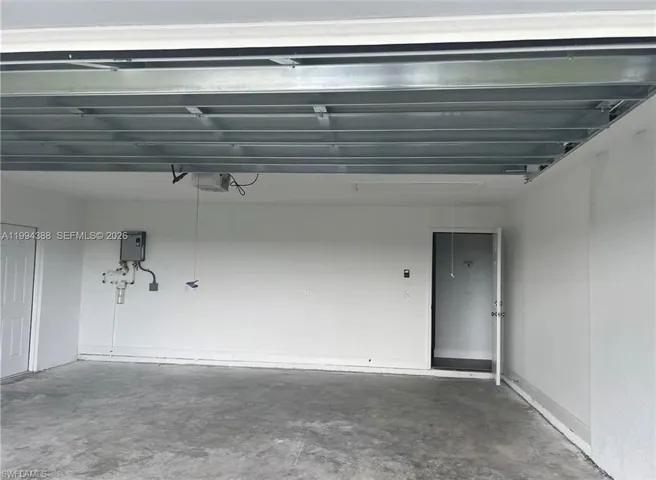 Spacious garage with a concrete floor, white painted walls, and a visible garage door opener mechanism