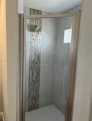 Walk-in shower with clear glass enclosure and brushed metal trim