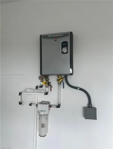 Wall-mounted tankless water heater with digital display, brass valves, and water filtration system