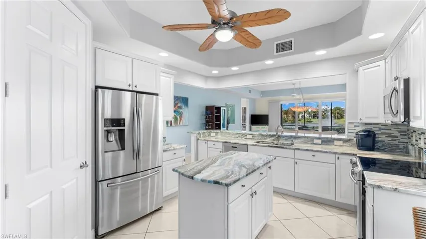 Kitchen with white cabinetry, appliances with stainless steel finishes, and a tray ceiling