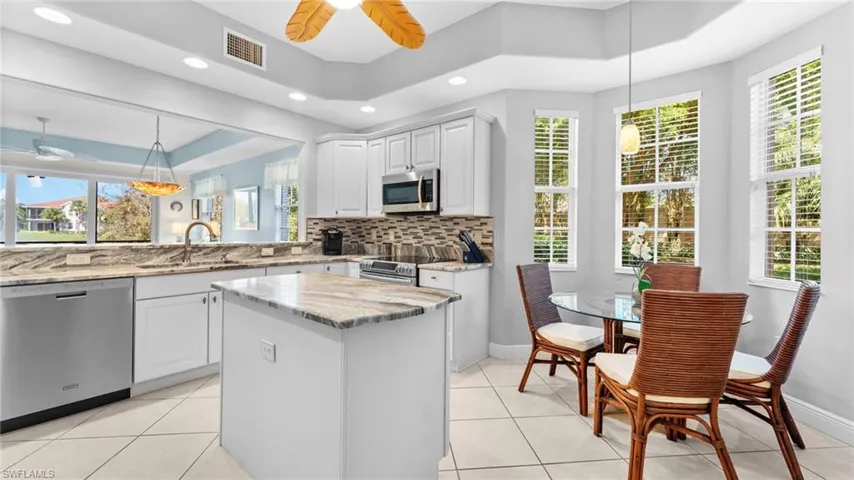 Kitchen featuring sink, white cabinets, decorative light fixtures, and appliances with stainless steel finishes