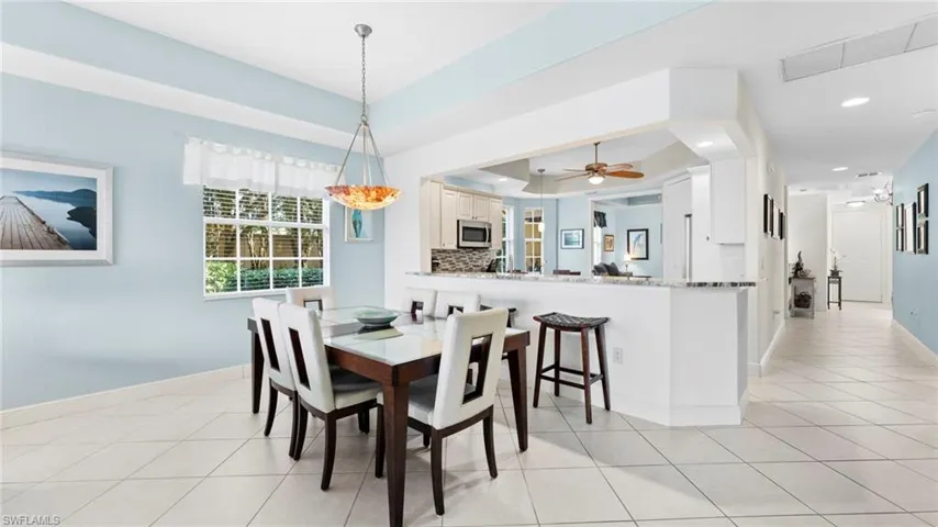 Dining space with ceiling fan, light tile patterned flooring, and a tray ceiling