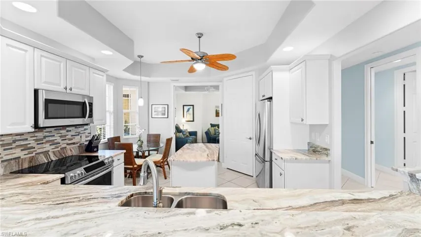 Kitchen featuring white cabinetry, sink, ceiling fan, decorative backsplash, and appliances with stainless steel finishes