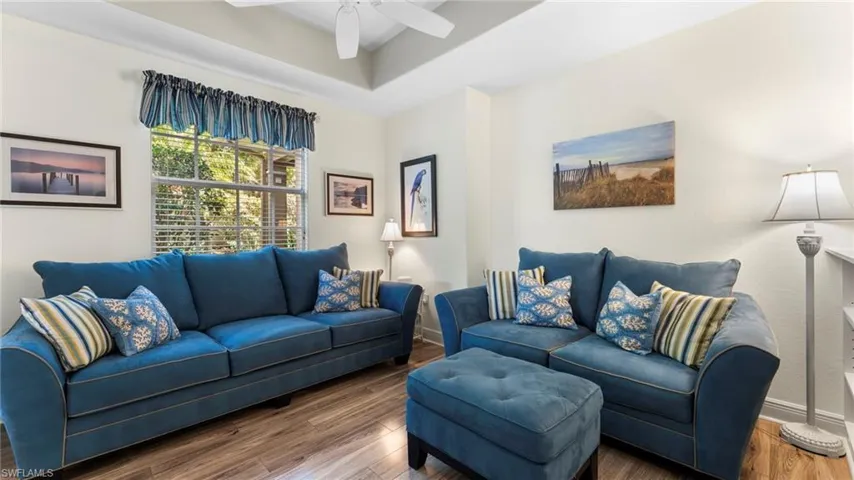 Living room with ceiling fan and dark wood-type flooring