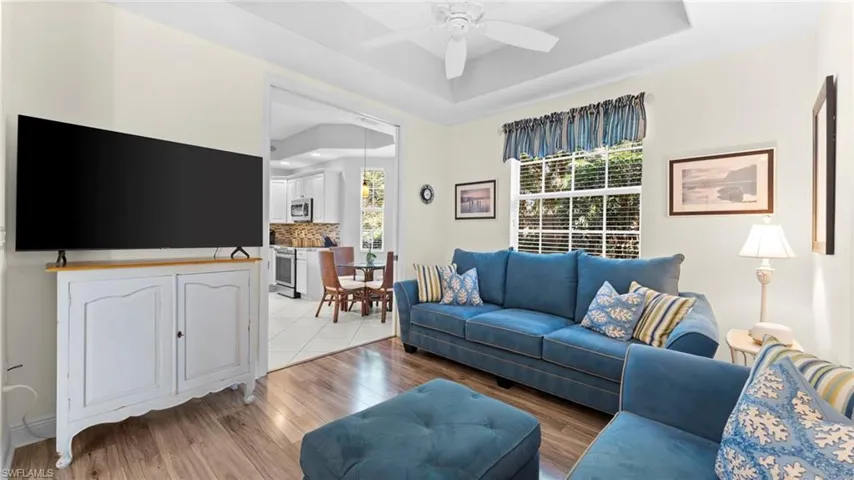 Living room featuring a tray ceiling, light hardwood / wood-style flooring, and ceiling fan
