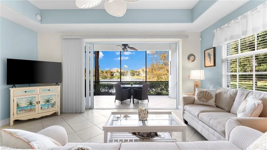 Tiled living room featuring a tray ceiling and a healthy amount of sunlight
